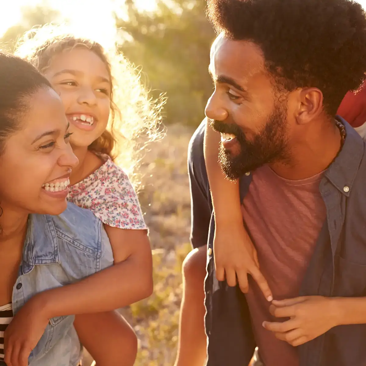 A happy family of four shares a piggyback ride outdoors.