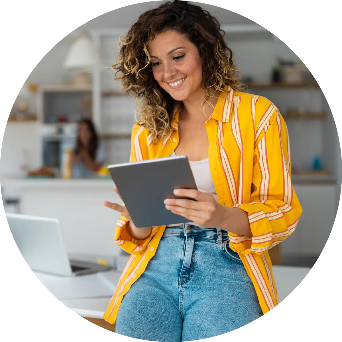 Woman leaning against a desk looking at the tablet in her hands.