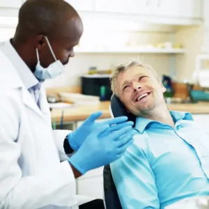 Dentist discussing treatment options with a male patient seated in a dental chair.