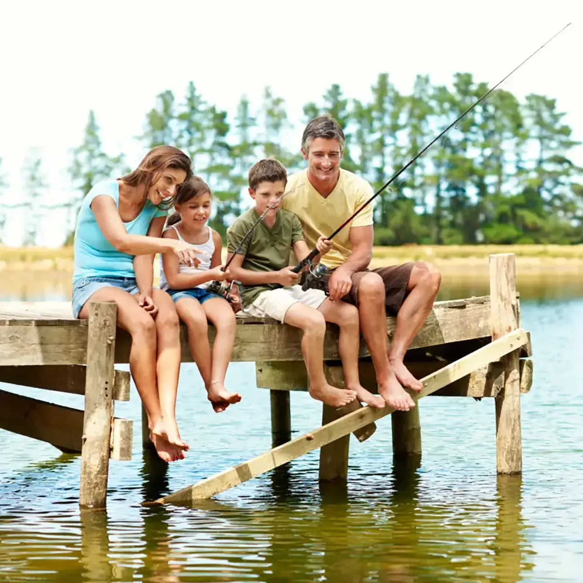 Family of four sitting on a dock fishing, including mom, dad, daughter, and son.