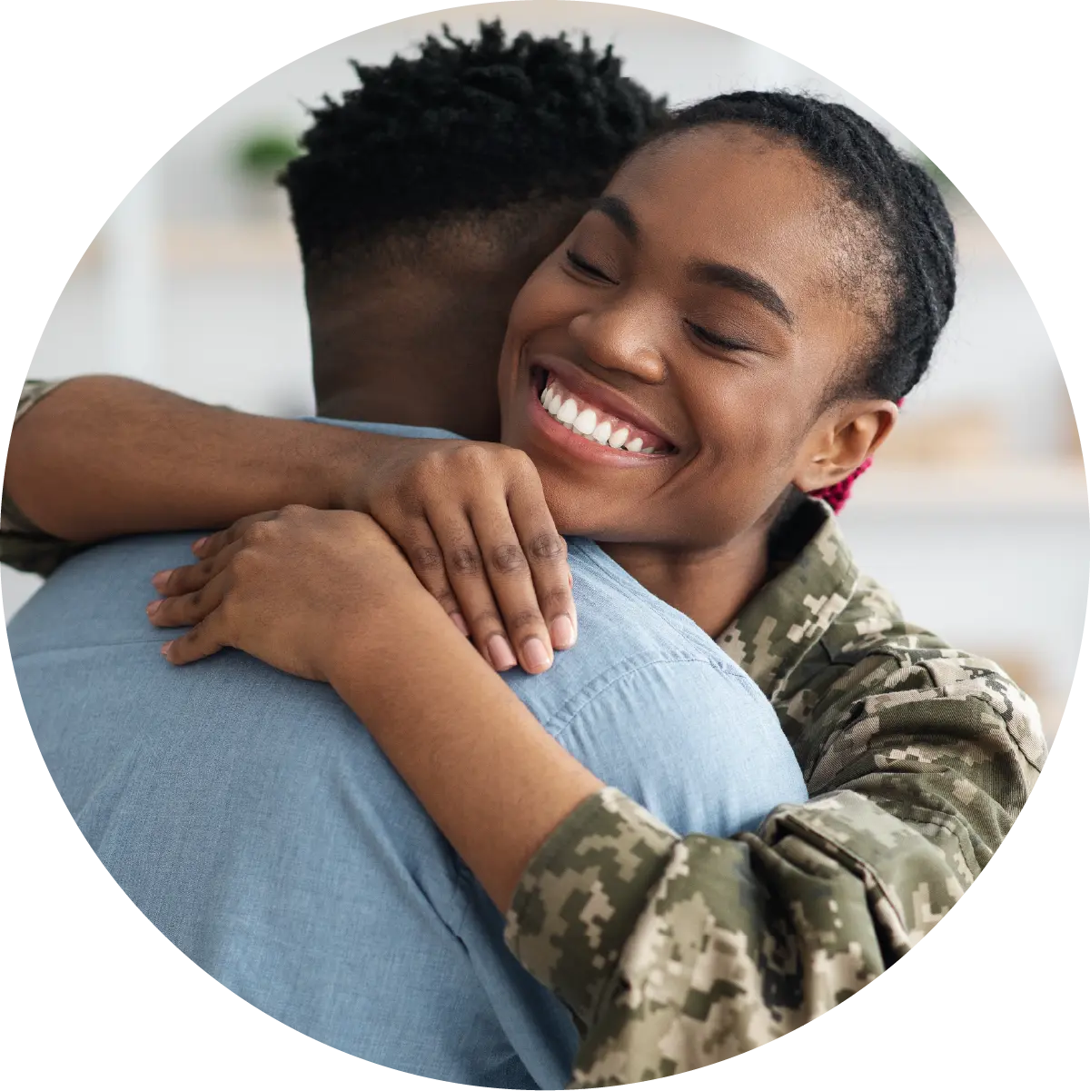 Smiling young woman in military uniform embraces a man, whose back is turned to the camera.