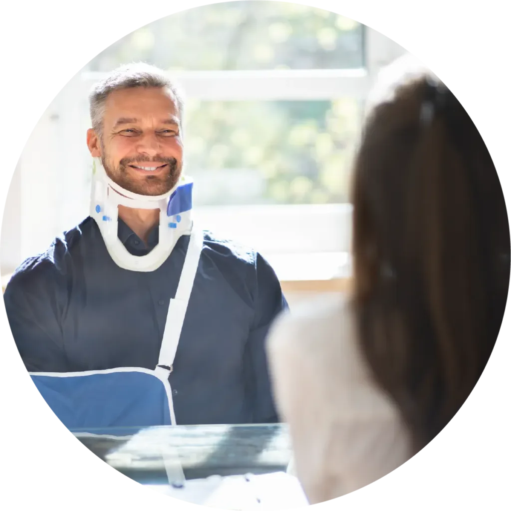 Smiling man, wearing a medical neck brace, is conversing with an individual, whose back is turned towards the camera.