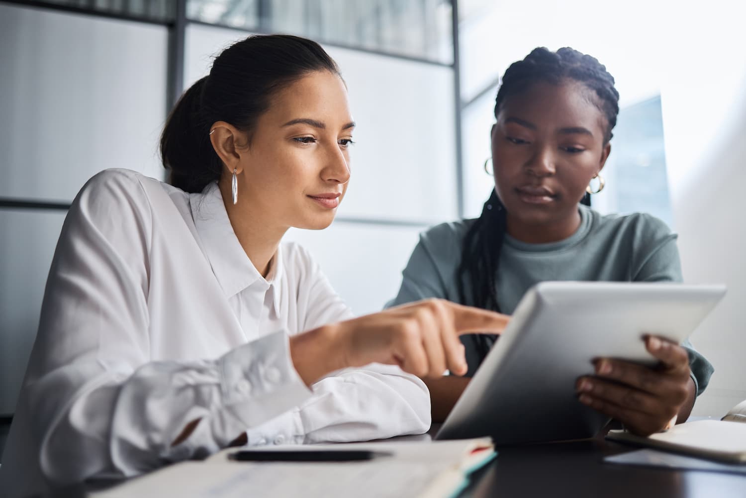Two women in office wear looking at a tablet