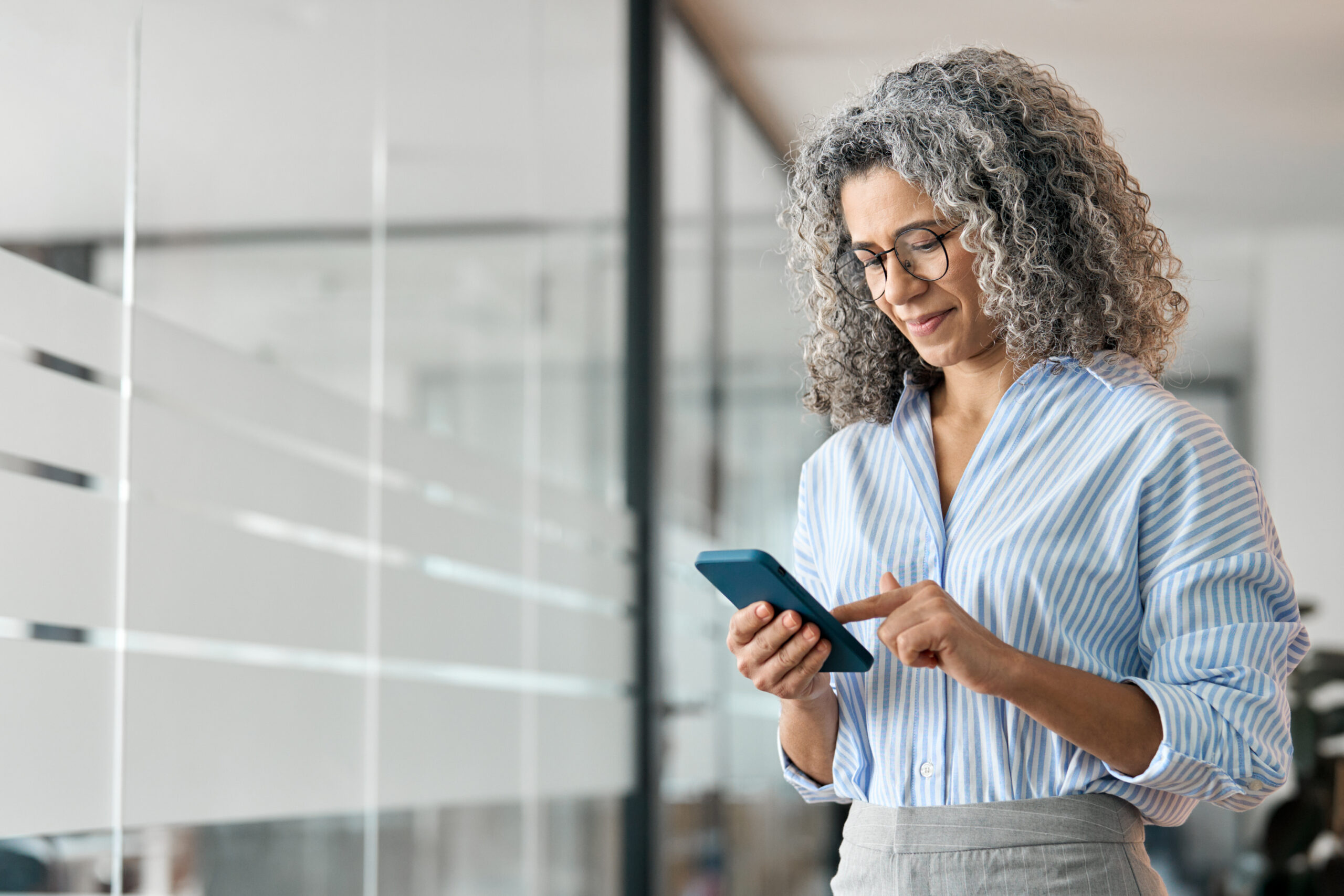 Woman in an office using a smartphone to access digital benefits information.